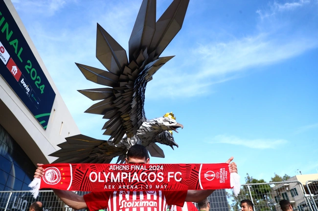 Φίλος του Ολυμπιακού με κασκόλ, μπροστά από τον αετό της ΑΕΚ