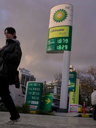 Μια γυναίκα περνάει δίπλα από μια πινακίδα που δείχνει τις τρέχουσες τιμές καυσίμων έξω από ένα βενζινάδικο στην Αθήνα, Ελλάδα, την Τετάρτη 11 Μαρτίου 2026. (AP Photo/Petros Giannakouris)