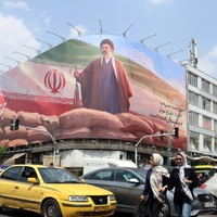 Ιρανοί περνούν δίπλα από μια μεγάλη πινακίδα του Ανώτατου Ηγέτη του Ιράν Αγιατολάχ Μοτζτάμπα Χαμενεΐ σε έναν δρόμο στην Τεχεράνη