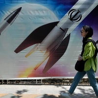 Μια γυναίκα περνάει δίπλα από ένα πανό που δείχνει πυραύλους να εκτοξεύονται, στη βόρεια Τεχεράνη 