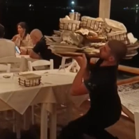 Σερβιτόρος σηκώνει φορτωμένο δίσκο στον έναν ώμο