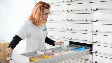 Φαρμακοποιός μπροστά σε ανοιχτό συρτάρι με φάρμακα