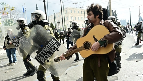 Μουσικός παίζει κιθάρα εν μέσω των επεισοδίων στο Σύνταγμα