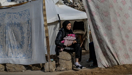 Μια Παλαιστίνια κρατάει ένα μωρό καθώς κάθεται έξω από τη σκηνή της οικογένειάς της στη γειτονιά Al Zaitun, ανατολικά της πόλης της Γάζας