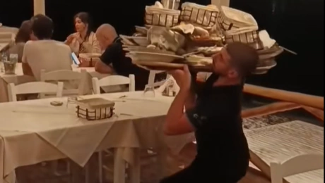 Σερβιτόρος σηκώνει φορτωμένο δίσκο στον έναν ώμο