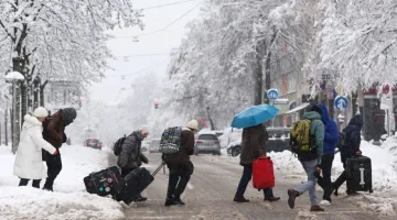 Ταξιδιώτες με τις βαλίτσες τους σε χιονισμένο δρόμο του Μονάχου
