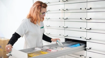 Φαρμακοποιός μπροστά σε ανοιχτό συρτάρι με φάρμακα