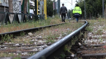 Άνδρες περπατούν στις ράγες Προαστιακού