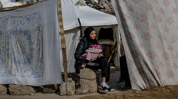 Μια Παλαιστίνια κρατάει ένα μωρό καθώς κάθεται έξω από τη σκηνή της οικογένειάς της στη γειτονιά Al Zaitun, ανατολικά της πόλης της Γάζας