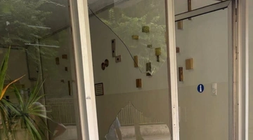 Το σπασμένο τζάμι στην είσοδο πολυκατοικίας μετά την άγρια επίθεση σε γυναίκα στο Αγρίνιο