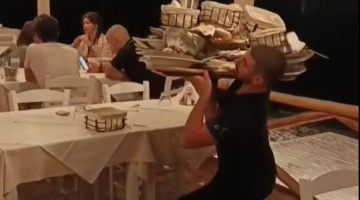 Σερβιτόρος σηκώνει φορτωμένο δίσκο στον έναν ώμο